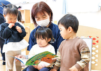 絵本を読んでいる園児と保育士