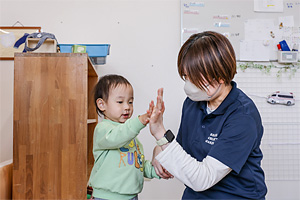 園児と保育士がハイタッチしている様子
